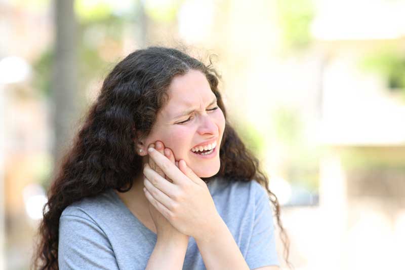 a woman is experiencing a severe jaw pain